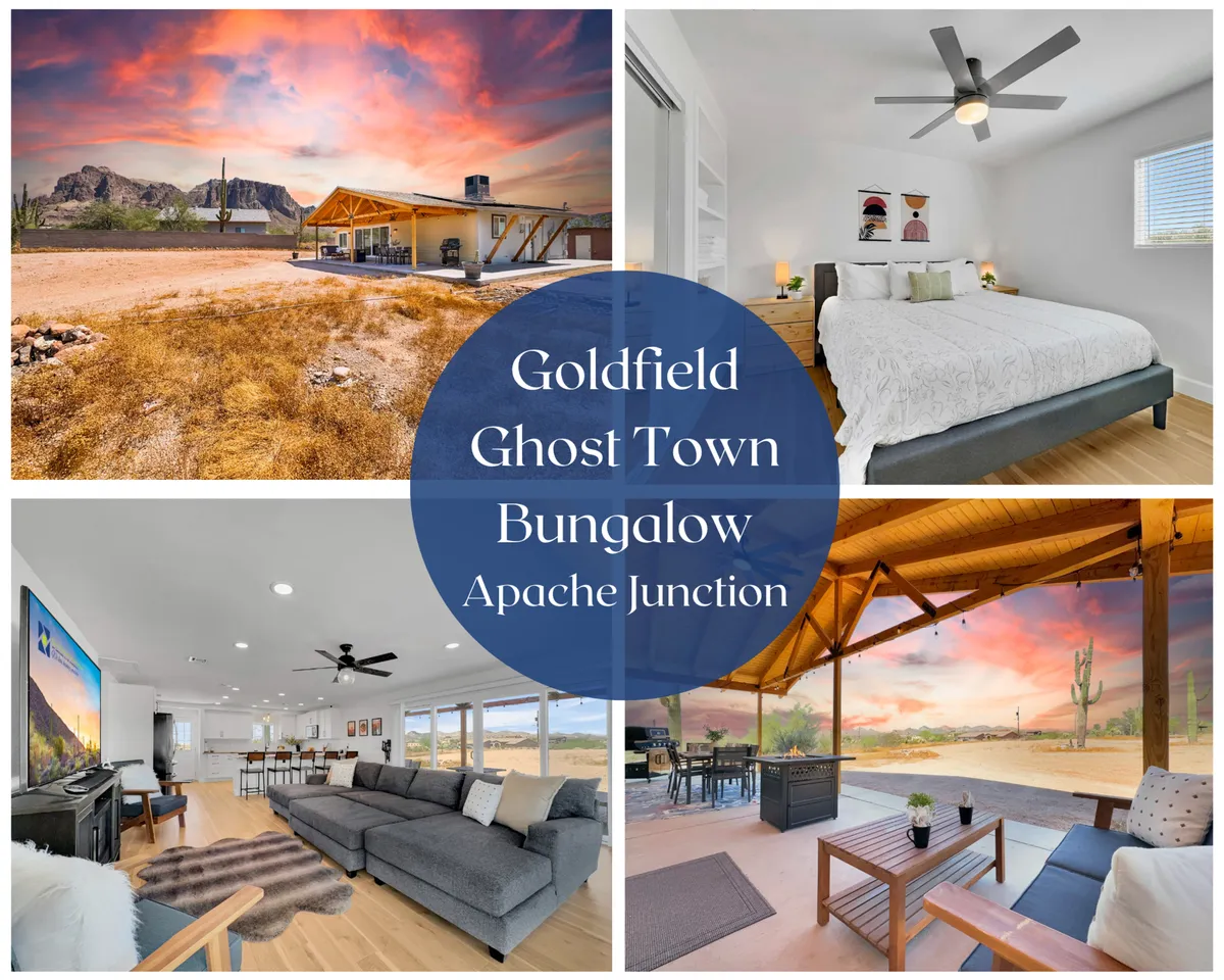 The image shows a beautifully remodeled bungalow set against the dramatic backdrop of the Superstition Mountains. The cozy patio is furnished for relaxation, with comfortable seating perfect for enjoying sunset views. The historic Goldfield Ghost Town is visible nearby, nestled within the striking desert landscape.