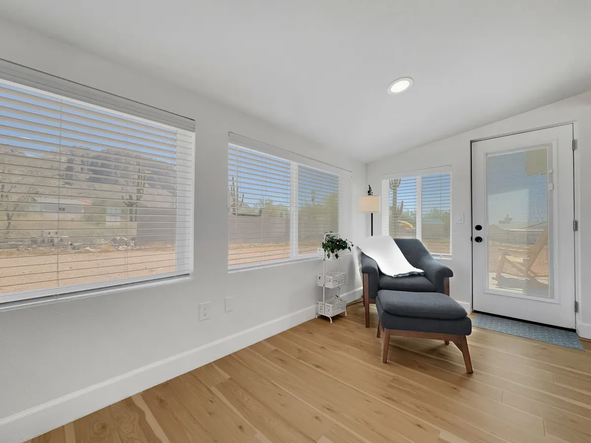 A tranquil corner with a comfortable chair positioned beside large windows and a door leading outside. Sunlight streams in, offering a serene spot for reading, relaxing, or enjoying the mountain view.