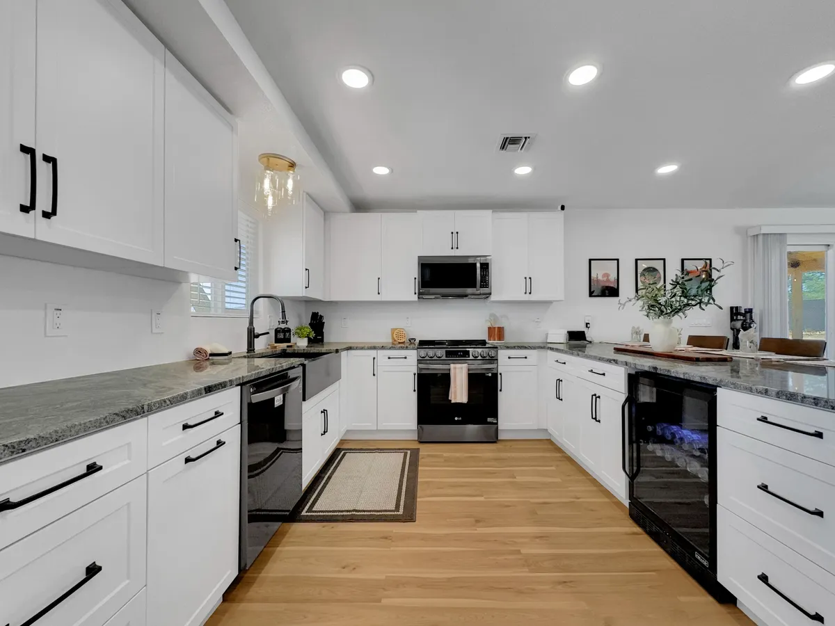 A beautifully remodeled kitchen featuring a spacious island with granite countertops, gleaming stainless steel appliances, and white cabinetry. The open layout invites natural light, making the space both modern and welcoming. The island offers ample seating, ideal for breakfast gatherings or dinner parties.