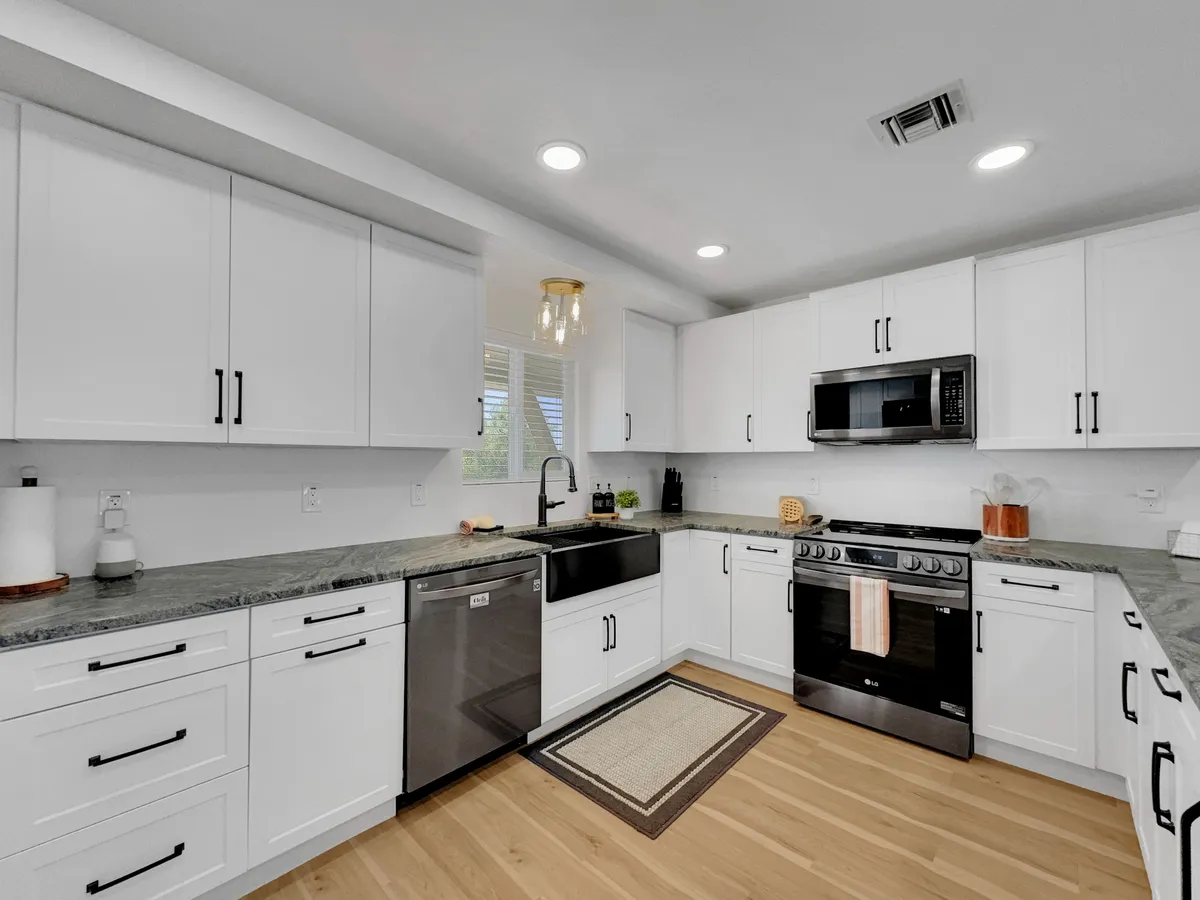 A bright, functional kitchen with a central island, stainless steel appliances, and abundant natural light streaming through a window. The sink area is integrated into the island, surrounded by ample counter space for meal preparation and casual dining.