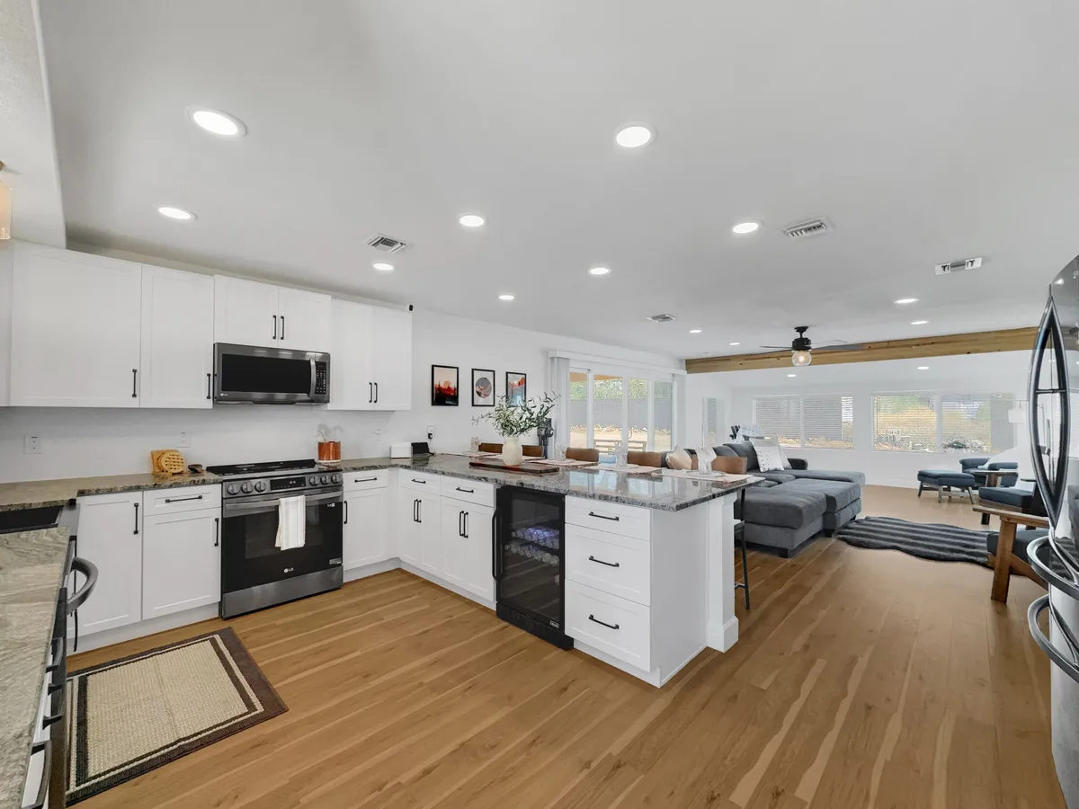 A spacious, modern kitchen with an island countertop, state-of-the-art appliances, and a dining area framed by large windows. The area exudes warmth and functionality, with ample space for cooking, entertaining, and group gatherings.