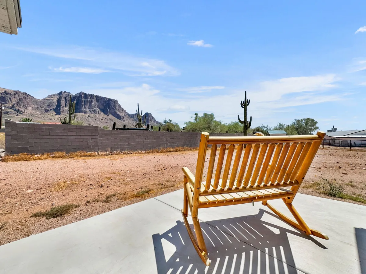 A wooden rocking chair overlooks a sweeping mountain landscape dotted with cacti, inviting guests to relax and soak in sunrise or sunset views. The setting emphasizes solitude and a direct connection with nature.